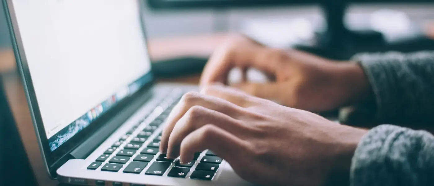 Hände tippen auf einer Laptop-Tastatur