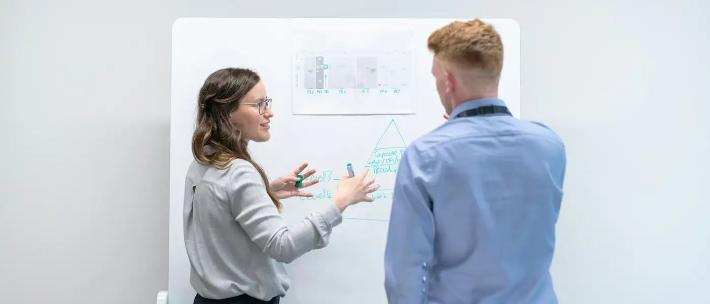 Zwei Personen besprechen sich vor einem Whiteboard